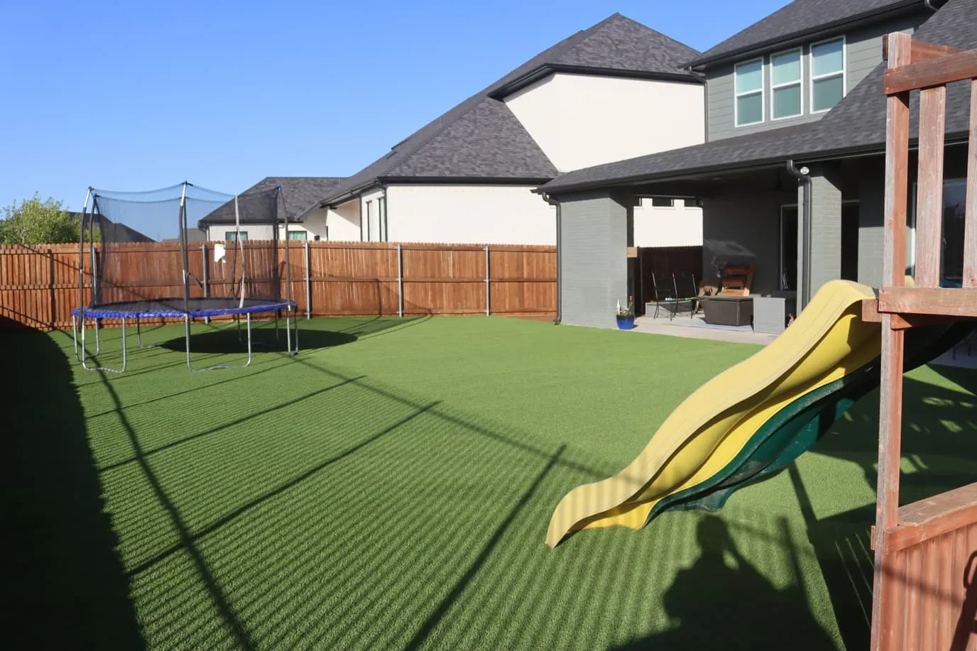Backyard artificial turf with trampoline and playset in North Texas