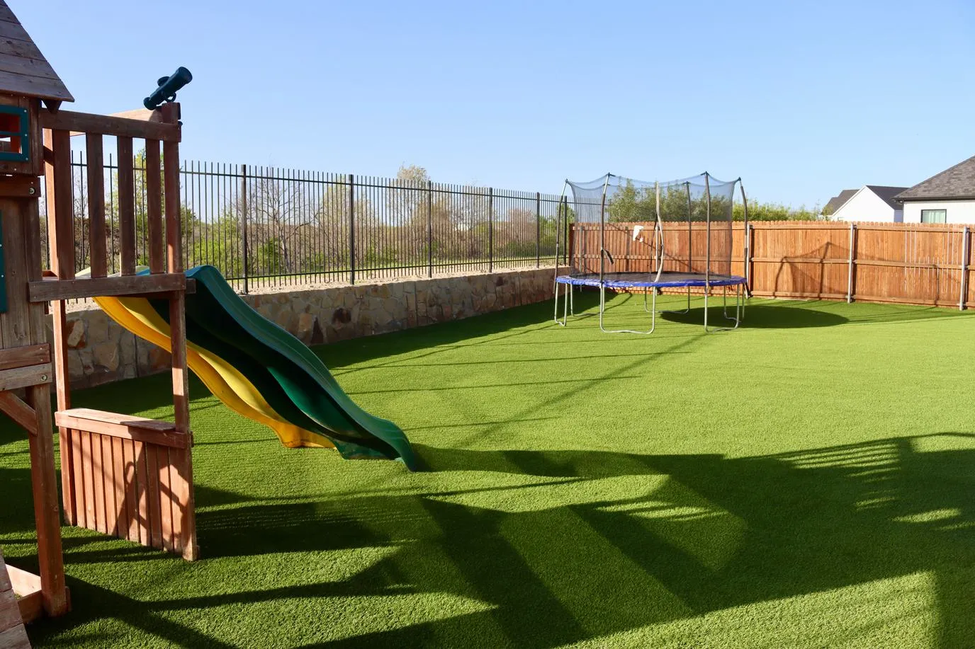 Artificial turf backyard with swing set and trampoline in DFW