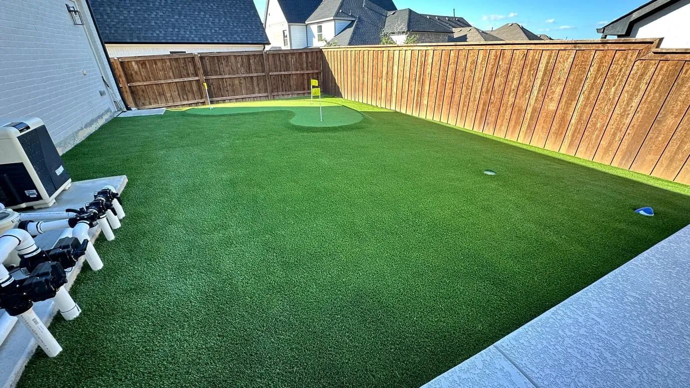 Backyard putting green with dark fringe and wood fence
