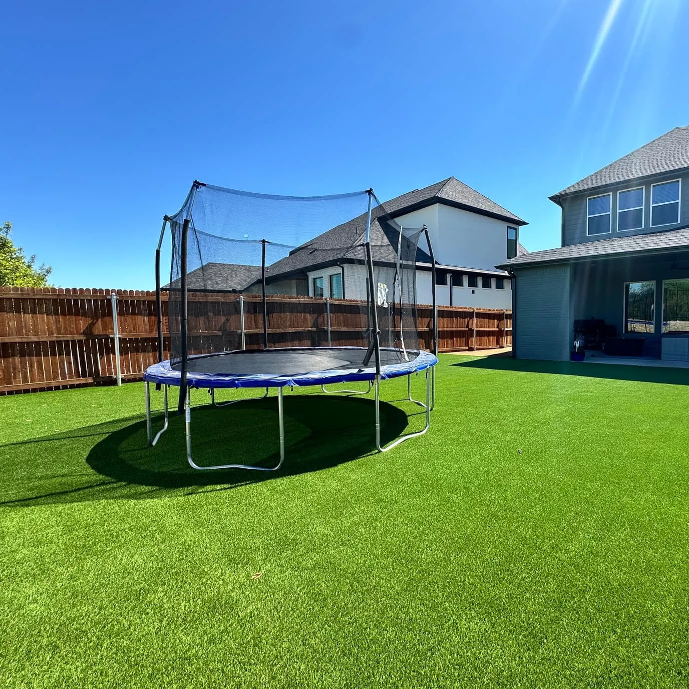 Backyard artificial turf with trampoline and two-story home