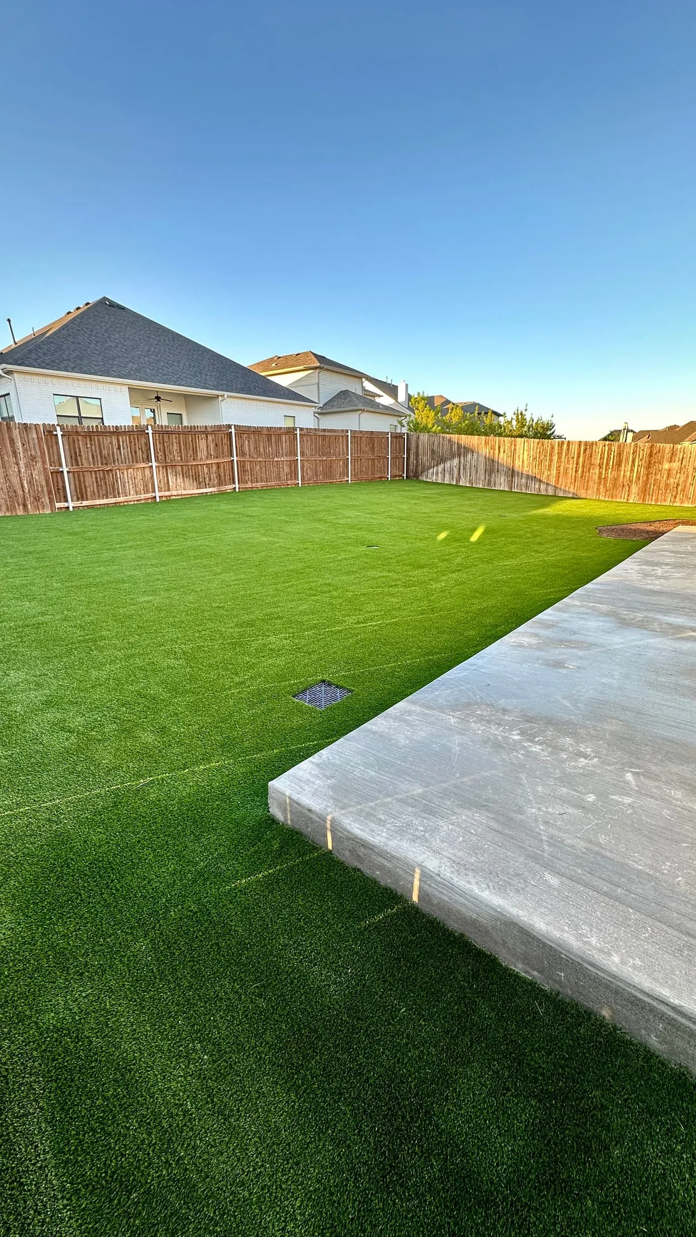 New backyard artificial turf with fresh patio slab in DFW