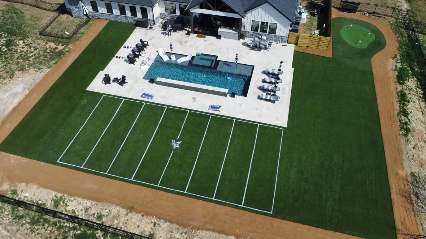 Aerial luxury estate with pool, sport court, and football turf in DFW