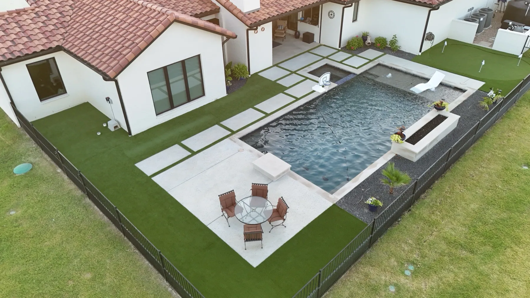 Aledo TX pool deck framed by artificial turf and backyard putting green