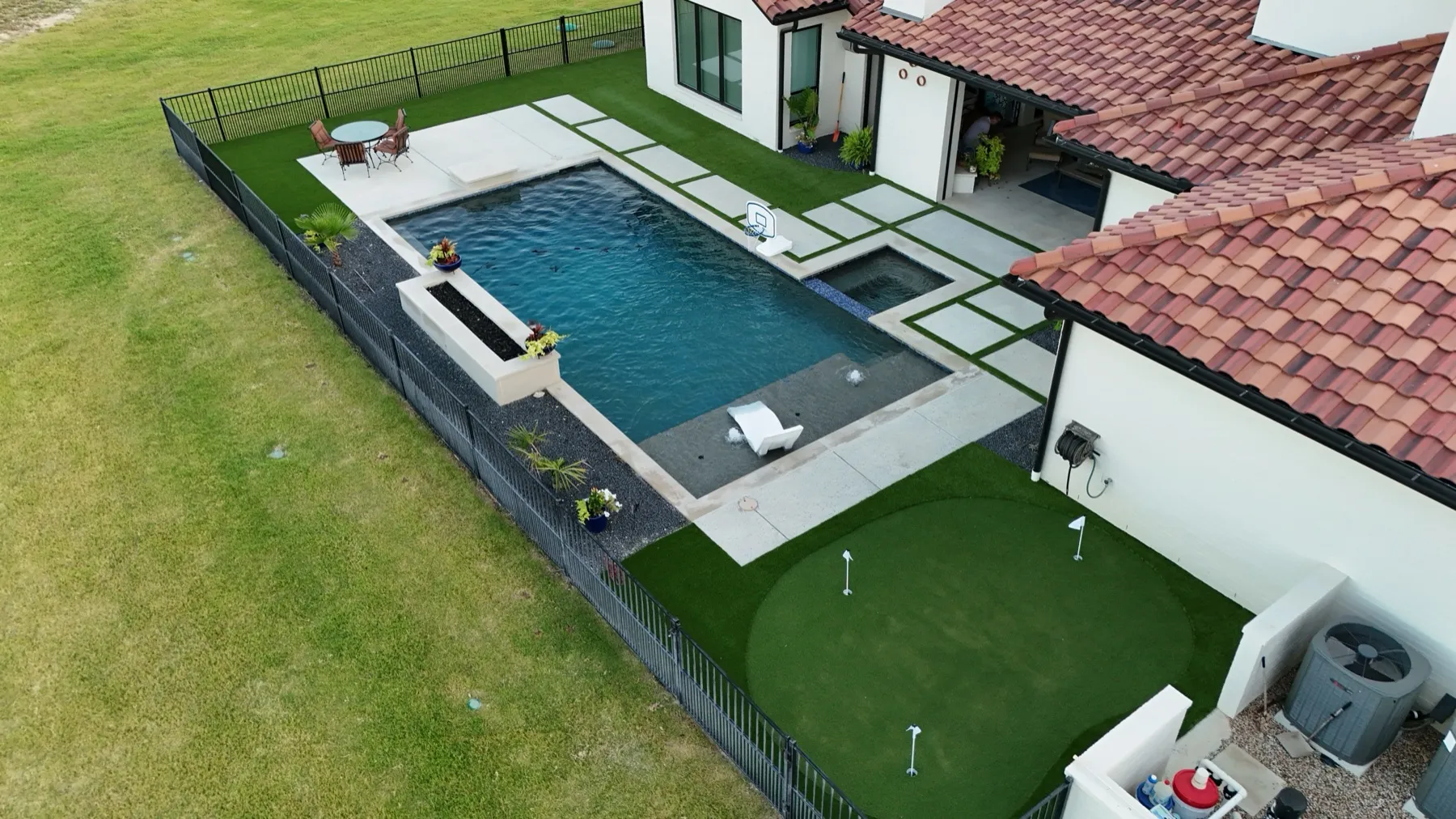 Backyard putting green and pool with artificial turf surround in Aledo, TX