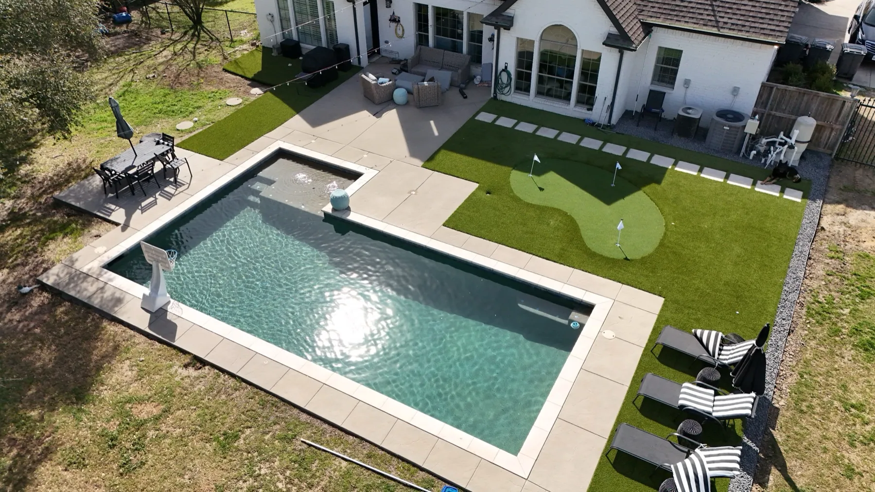 Residential backyard artificial turf with pool and patio