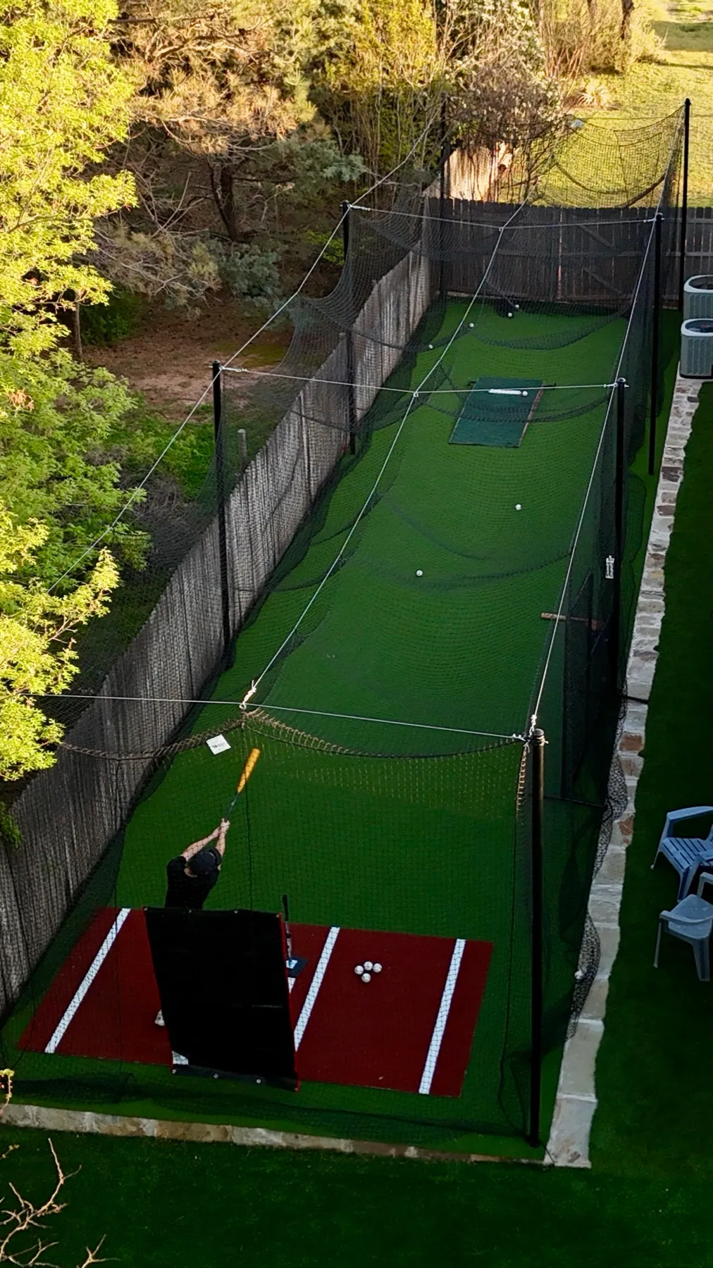 Vertical aerial of backyard batting cage with artificial turf in Aledo, TX