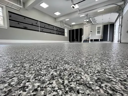 Wide view of a garage with a dark gray flake epoxy floor coating and slat-wall storage in DFW