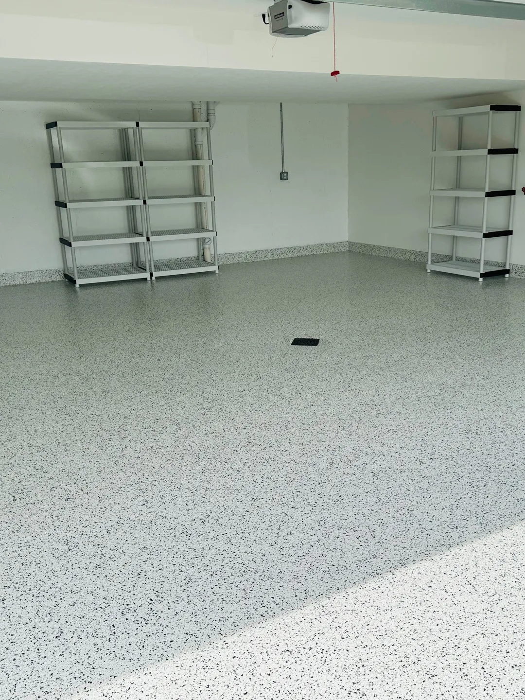 Light gray flake epoxy floor coating in an empty garage with metal storage shelving in DFW