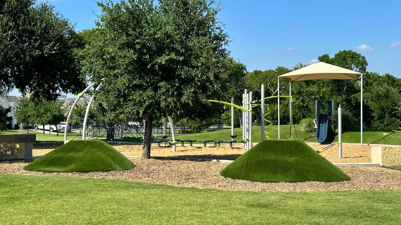 Commercial park playground with artificial turf mounds in DFW