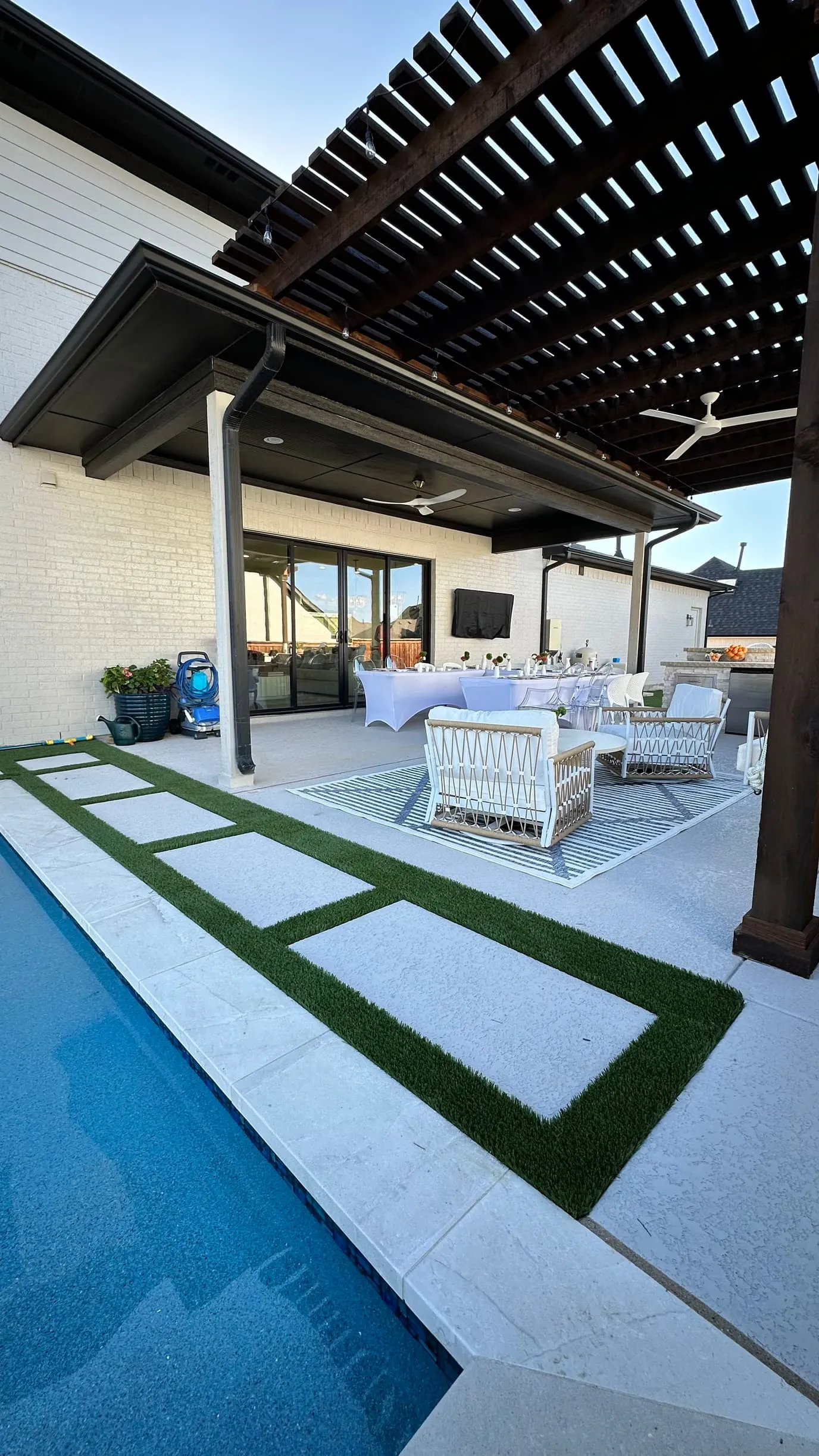 Poolside patio with turf-and-paver strips under pergola