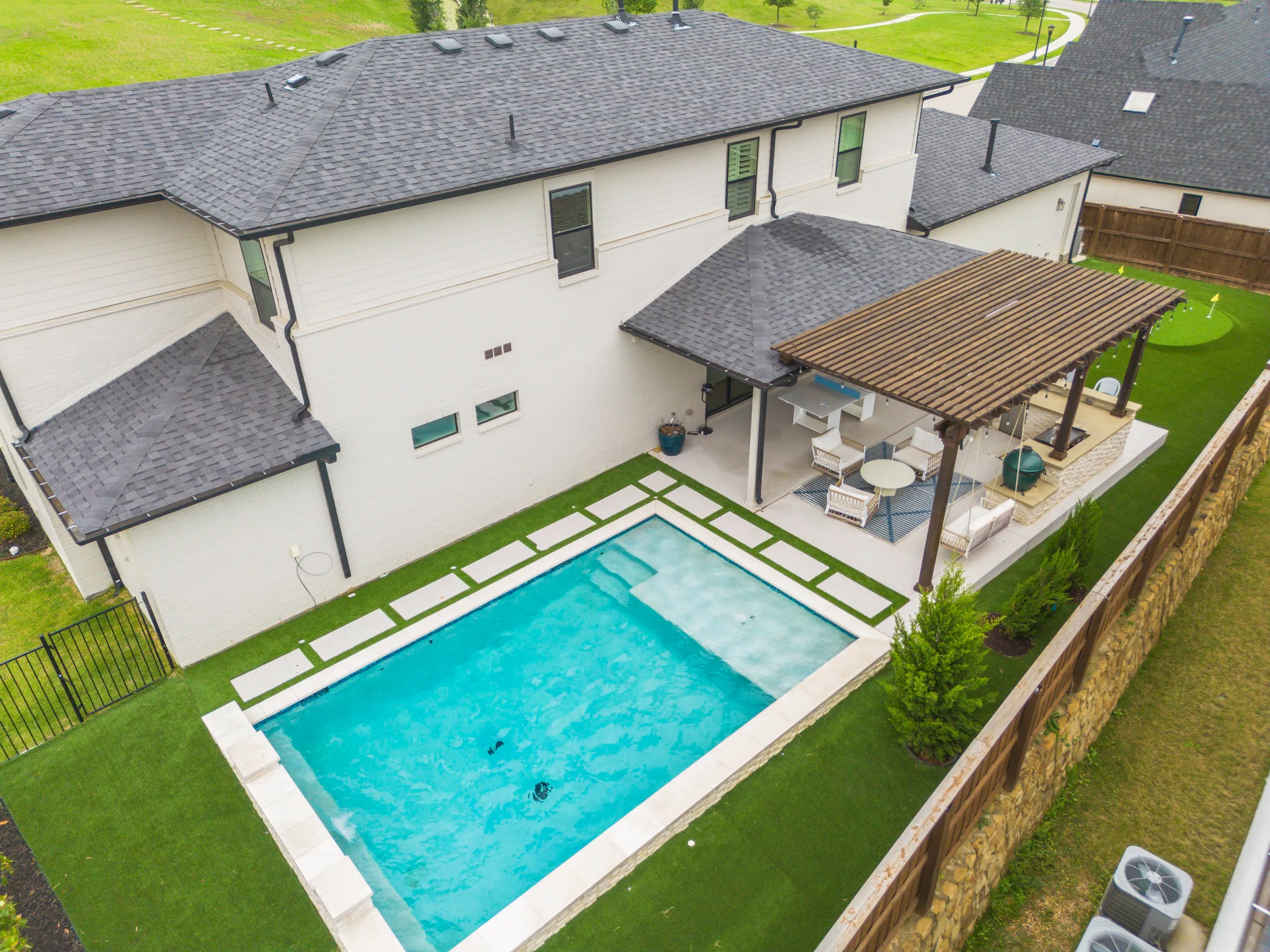 Aerial backyard pool with pergola and artificial turf
