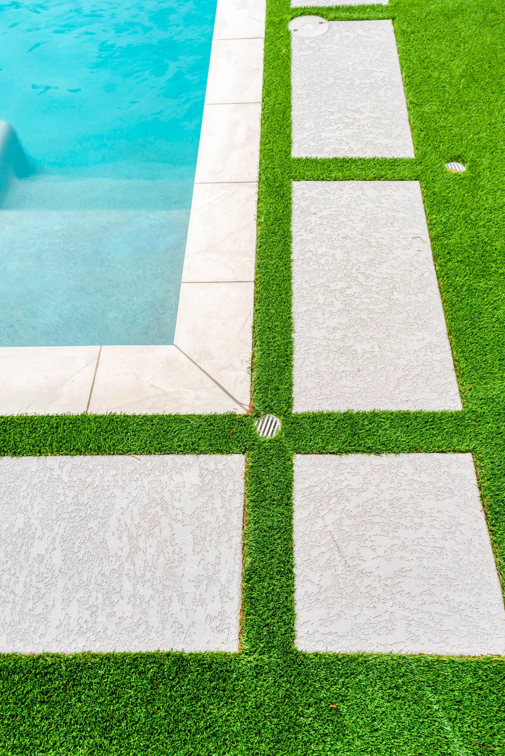 Artificial turf and paver joints beside a pool