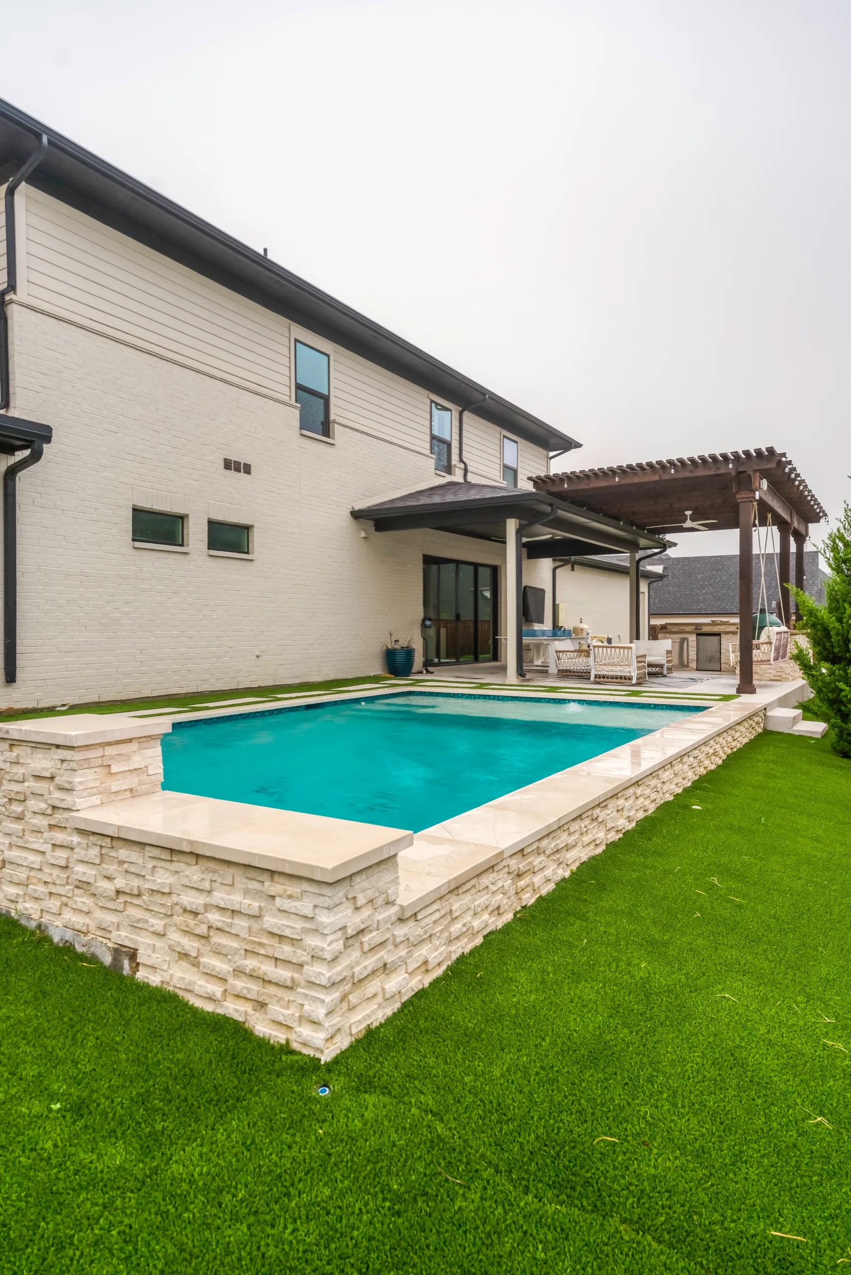 Modern vertical view of backyard pool with artificial turf perimeter