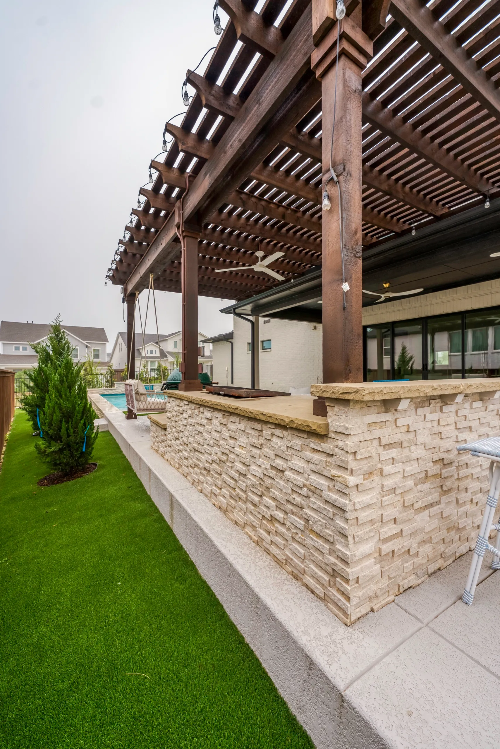 Pergola with stacked-stone bar and artificial turf in DFW