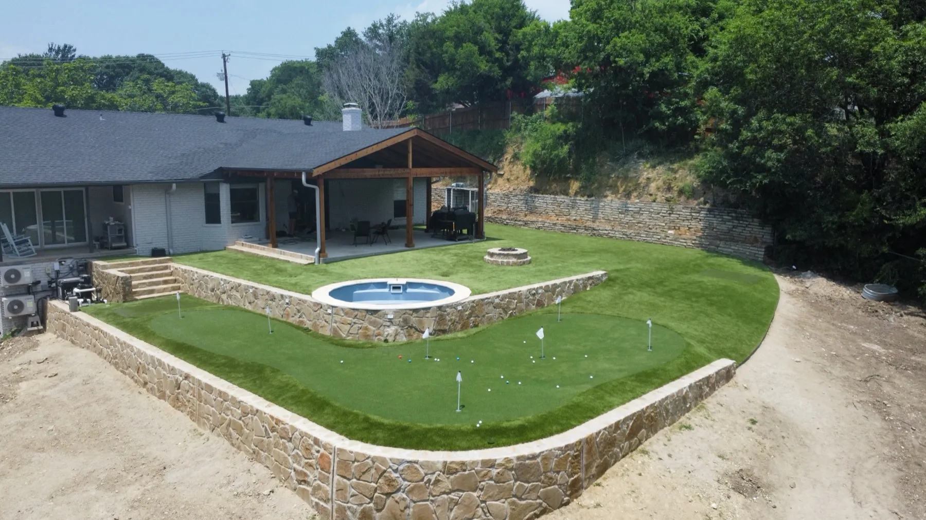 Aerial backyard putting green with flags and stock-tank pool in Willow Park