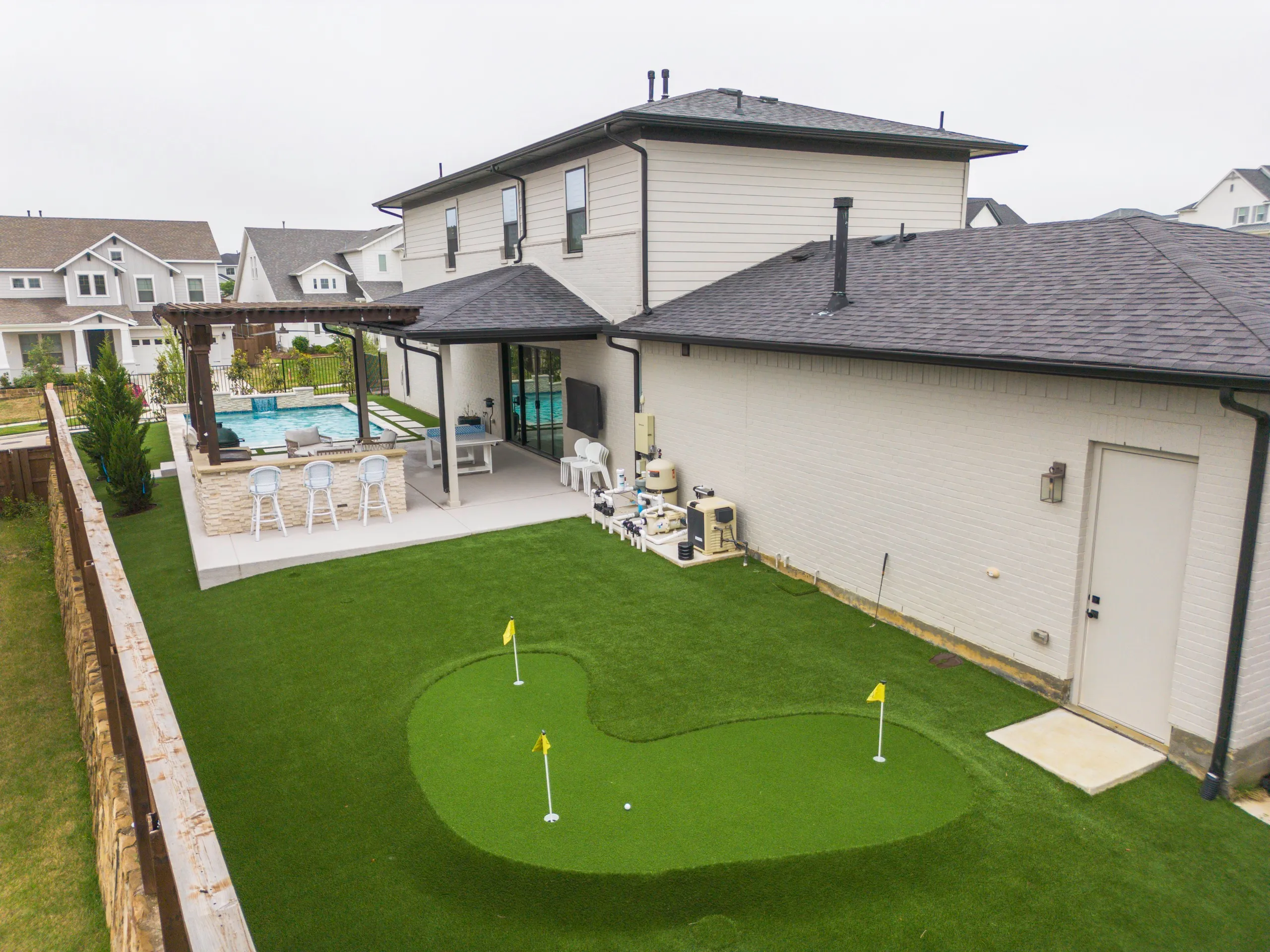 Aerial backyard putting green and pool with modern DFW home