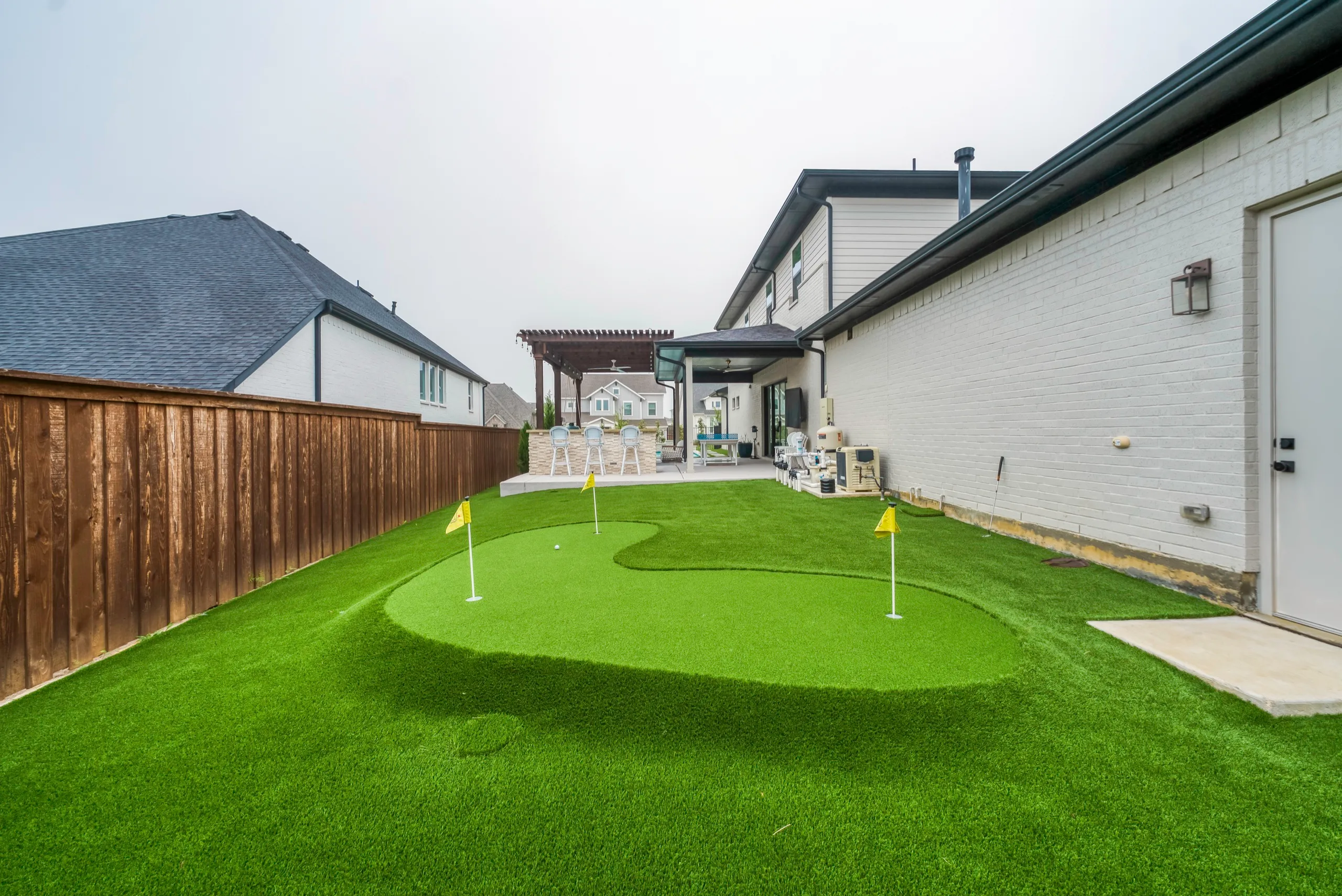 Backyard side-yard putting green with flags in DFW