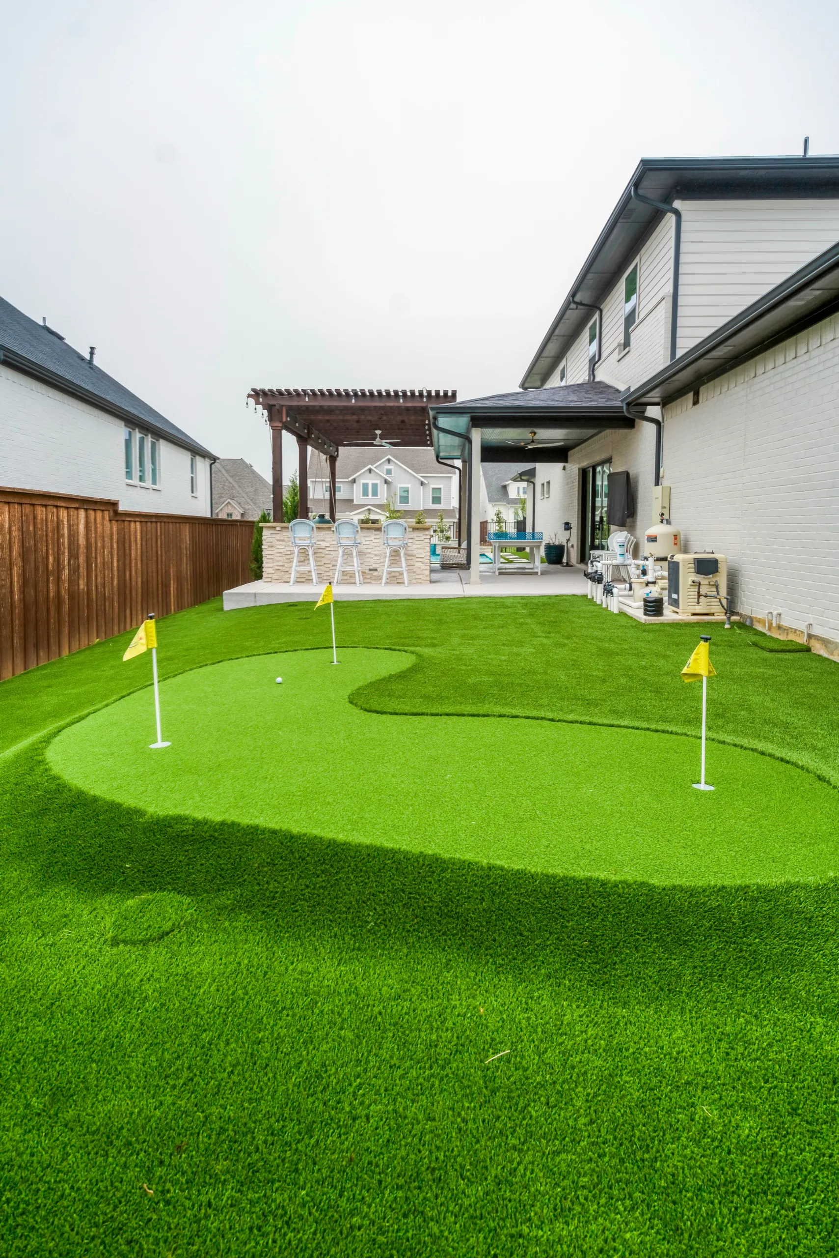 Vertical view of side-yard putting green with flags in DFW