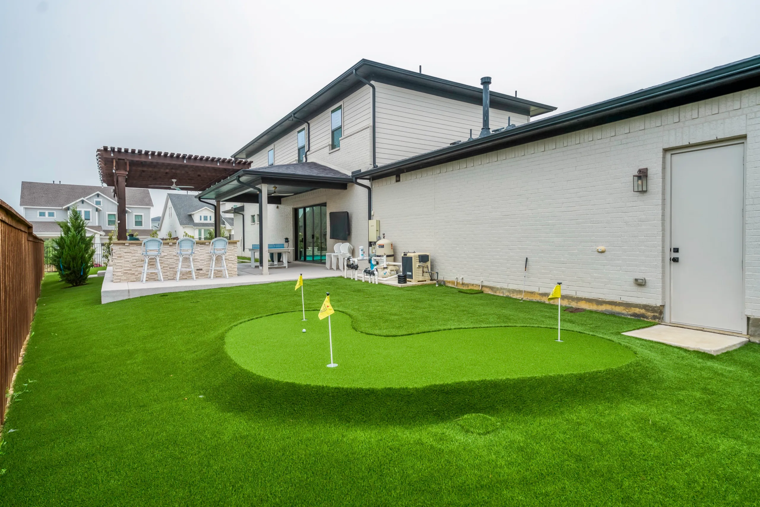 Backyard putting green with modern home and pergola