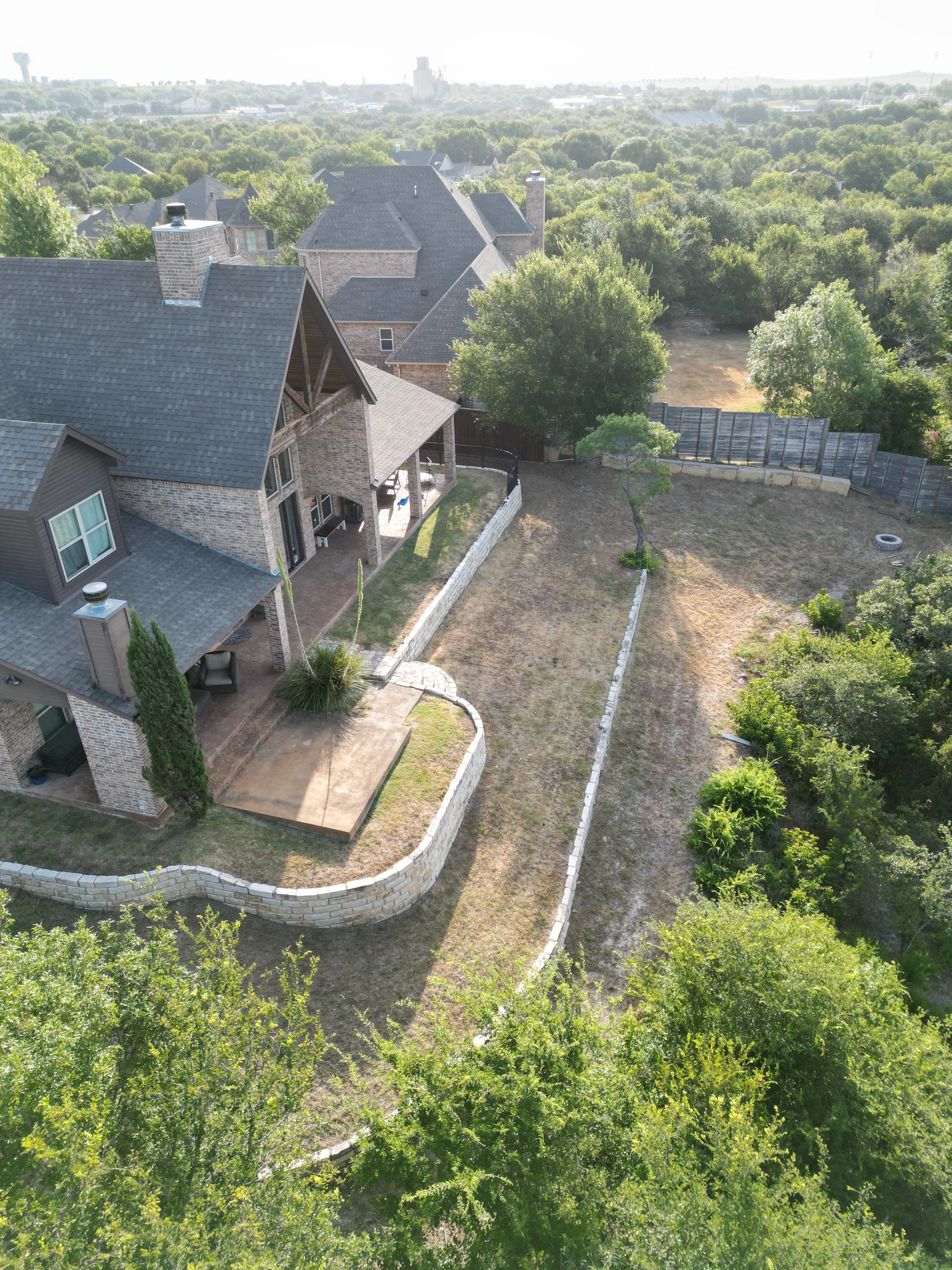 Aledo tiered backyard build: 606 SF Millsap retaining wall + 5,600 SF Bermuda Pro turf — before