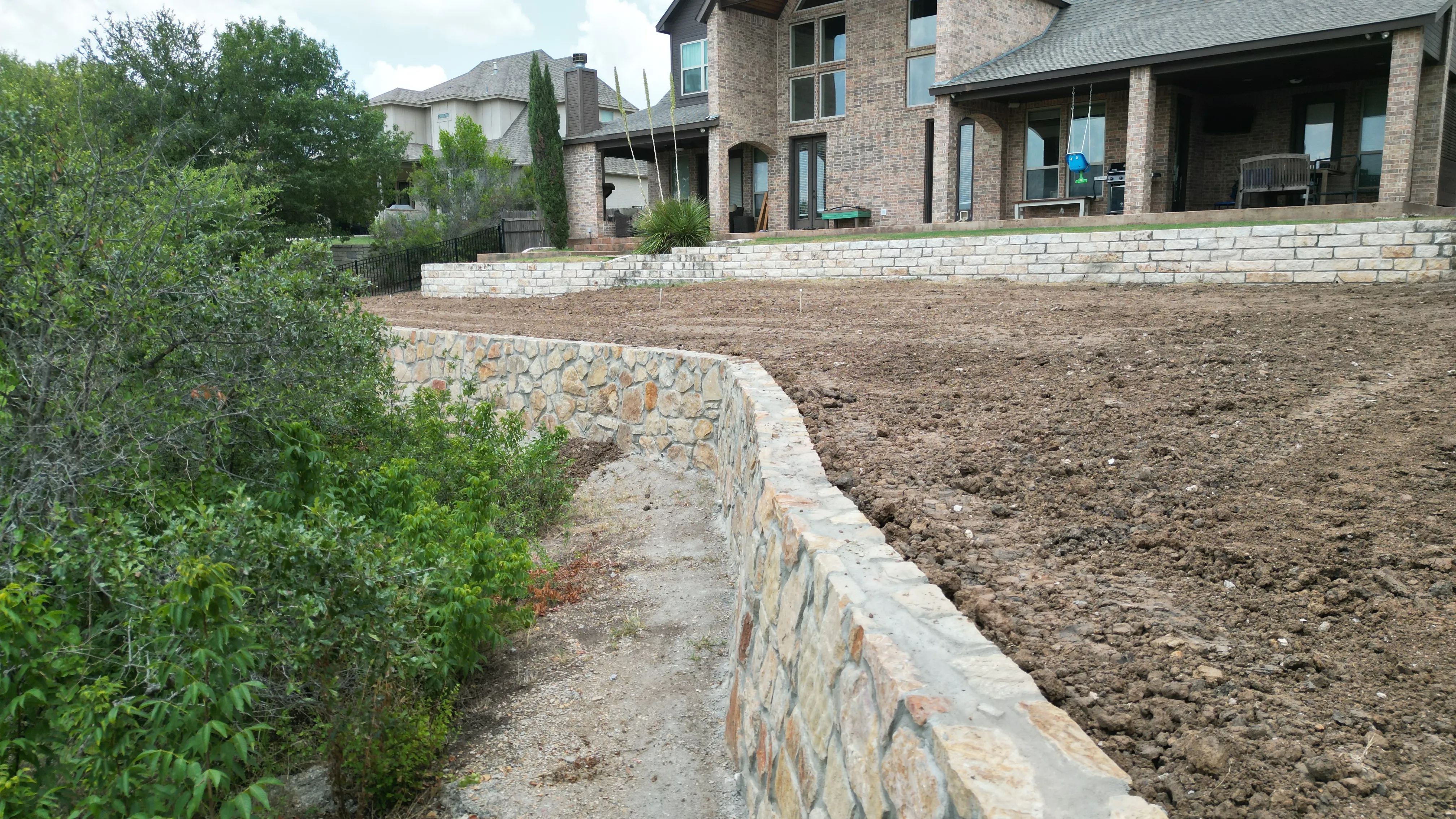 Construction 10 — Aledo tiered backyard build: 606 SF Millsap retaining wall + 5,600 SF Bermuda Pro turf