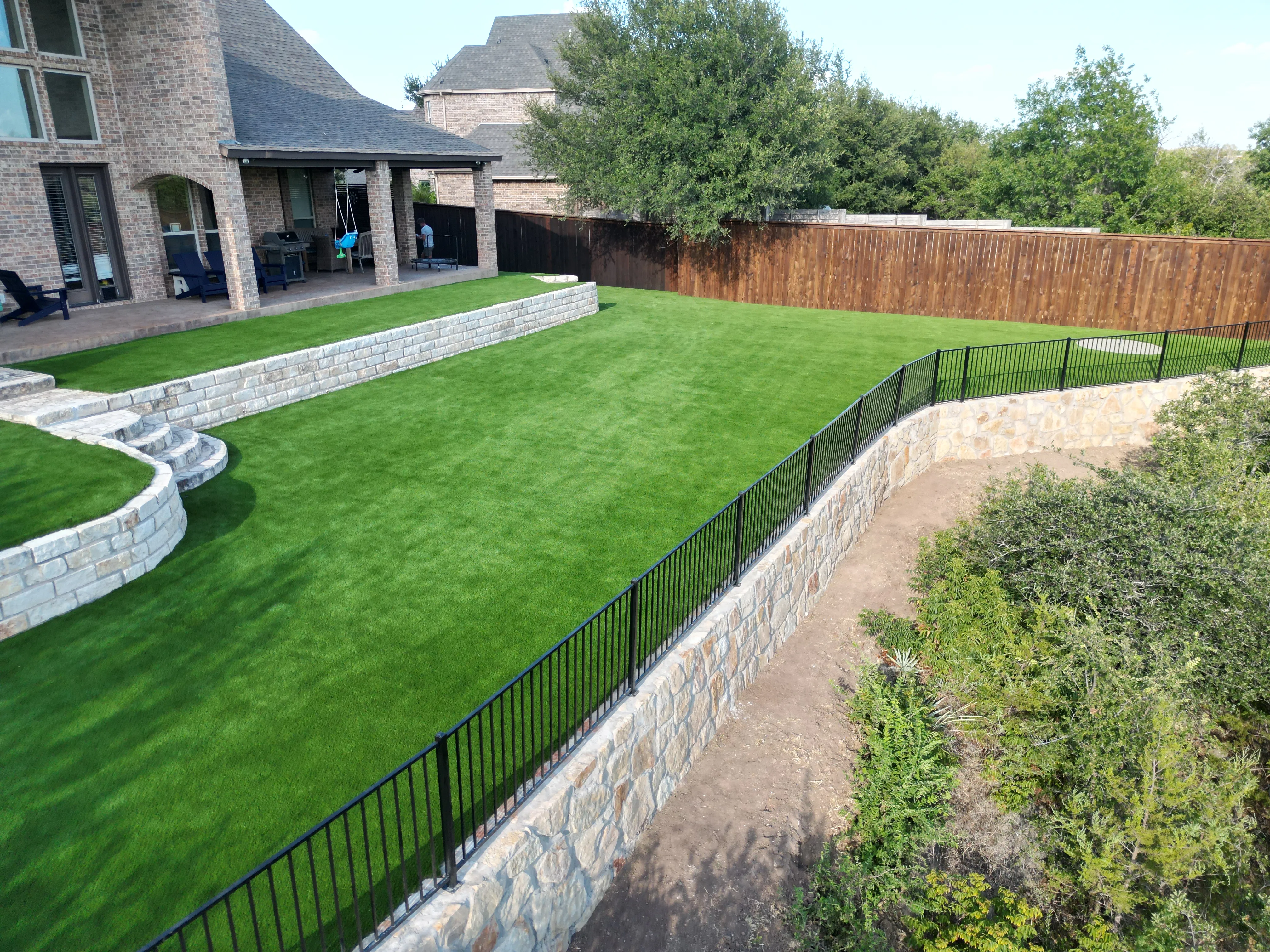 After 11 — Aledo tiered backyard build: 606 SF Millsap retaining wall + 5,600 SF Bermuda Pro turf