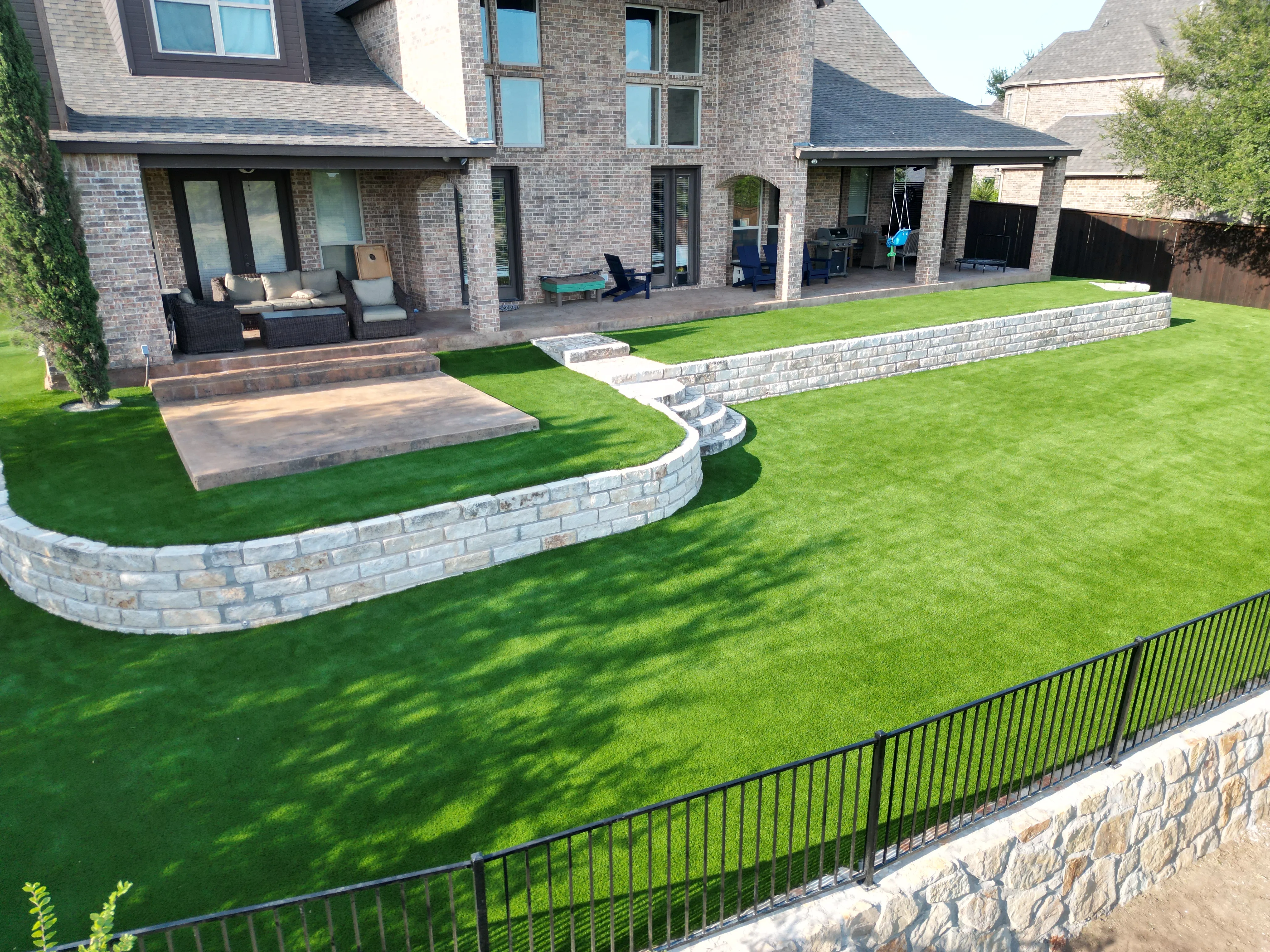 After 12 — Aledo tiered backyard build: 606 SF Millsap retaining wall + 5,600 SF Bermuda Pro turf