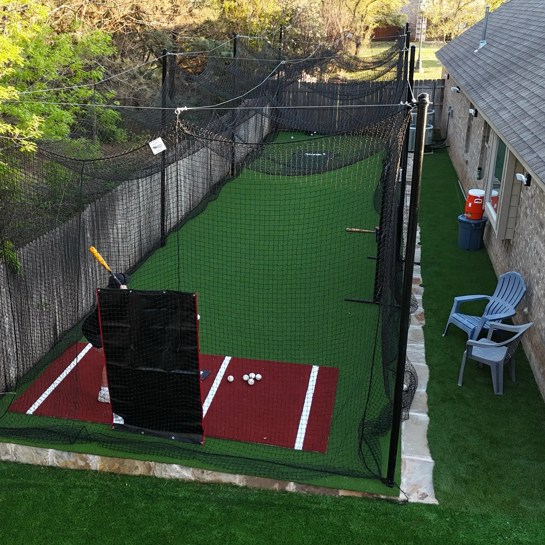 Drone aerial view of a Bearcat-installed backyard batting cage with surrounding turf and home in the background.