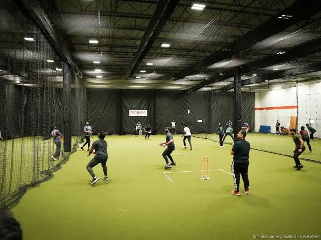 Indoor cricket facility with netting lanes and turf pitch