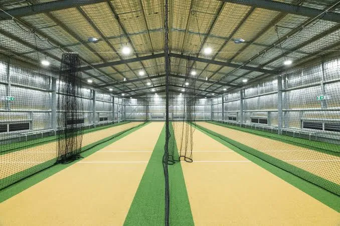 Example of a multi-lane indoor cricket facility with color-coded matting pitches and cable-hung netting between lanes