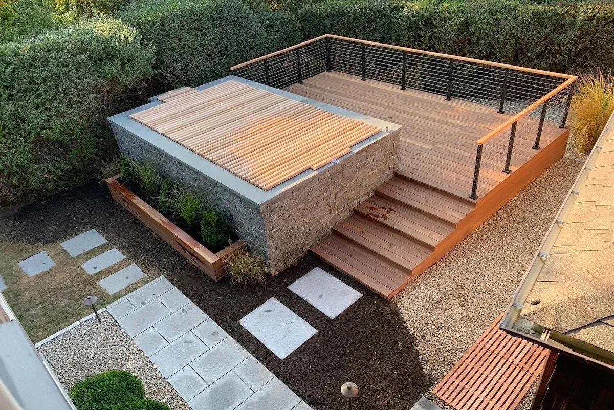 Soake precast plunge pool installed fully above ground with a stone surround, wooden roll cover, and cedar deck