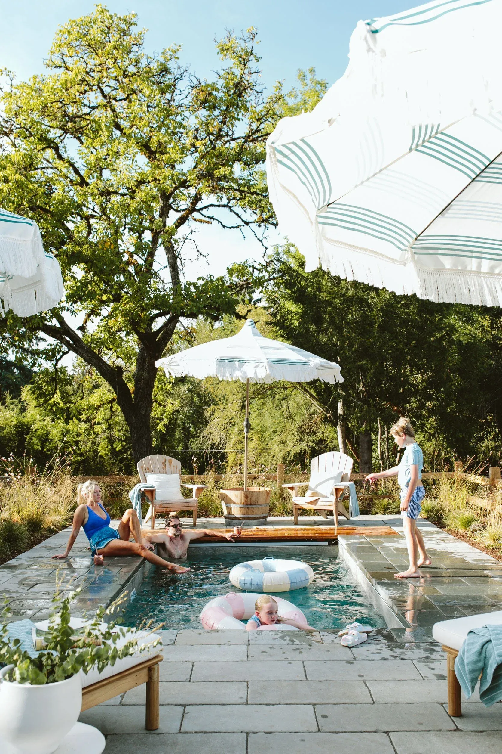 Family relaxing around a Soake precast plunge pool set flush into a stone patio deck